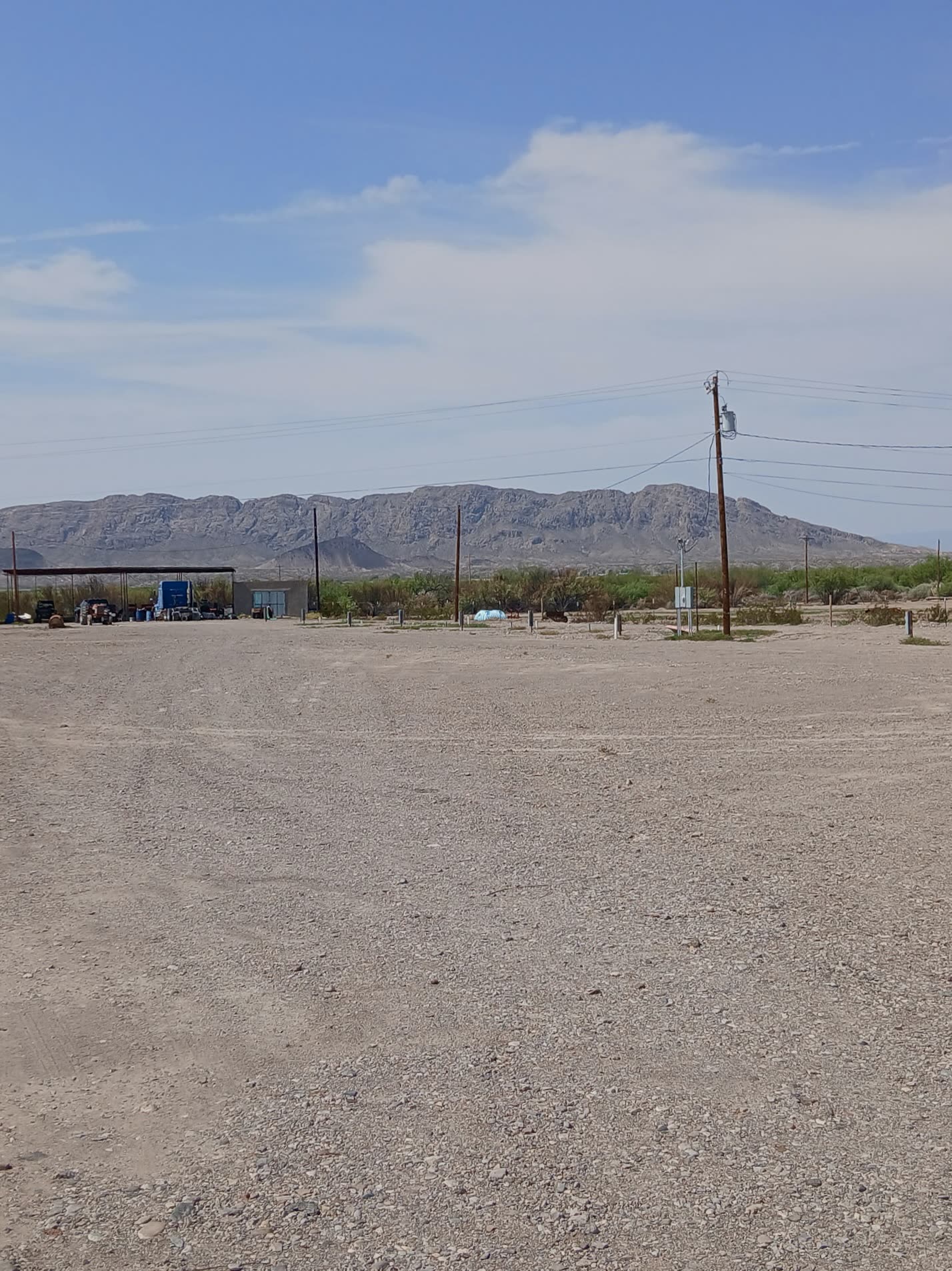 Gravel RV sites with utility pedestals at Santa Cruz Vista RV Park with desert mountains behind